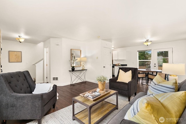 living room with dark wood finished floors, visible vents, and baseboards