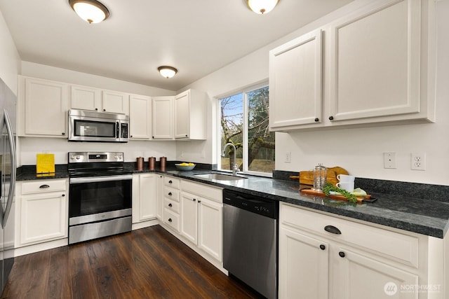 kitchen with white cabinets, appliances with stainless steel finishes, dark wood finished floors, and a sink