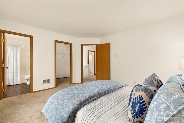 bedroom with baseboards, visible vents, a walk in closet, carpet floors, and a closet