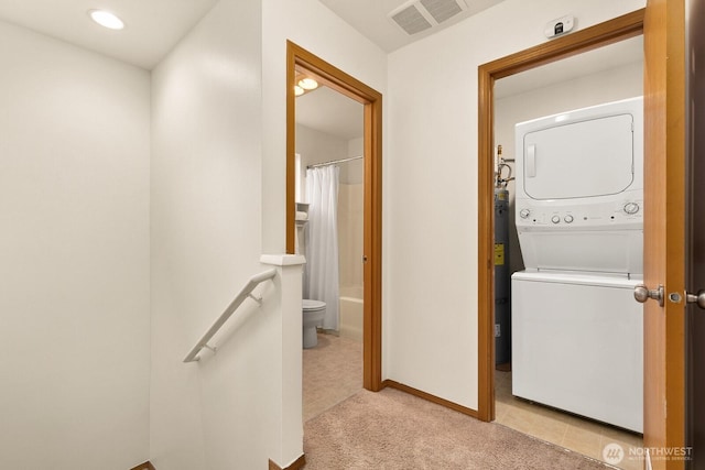 laundry area featuring stacked washer and dryer, visible vents, light carpet, laundry area, and baseboards