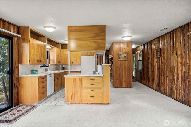 kitchen featuring light carpet, light countertops, white appliances, and wooden walls