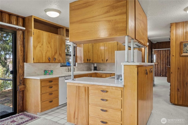 kitchen featuring white appliances, wood walls, a sink, light countertops, and backsplash