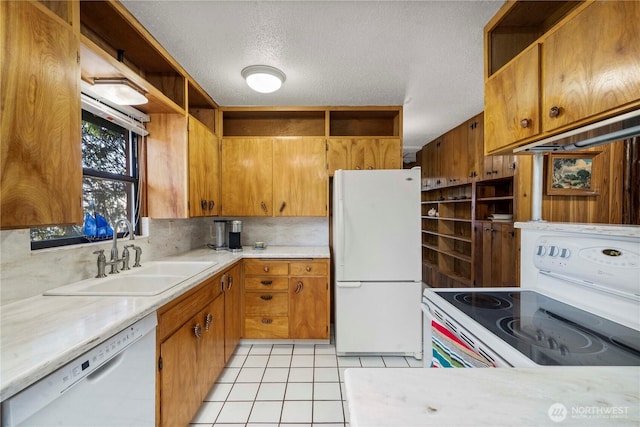 kitchen with light tile patterned floors, light countertops, brown cabinetry, a sink, and white appliances