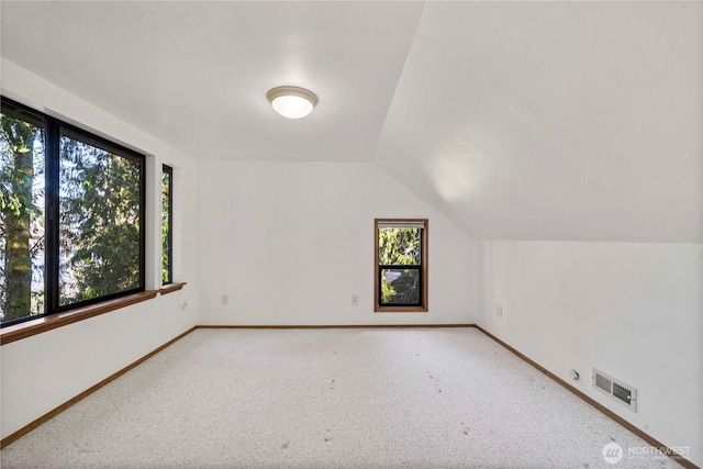 additional living space with lofted ceiling, carpet floors, baseboards, and visible vents