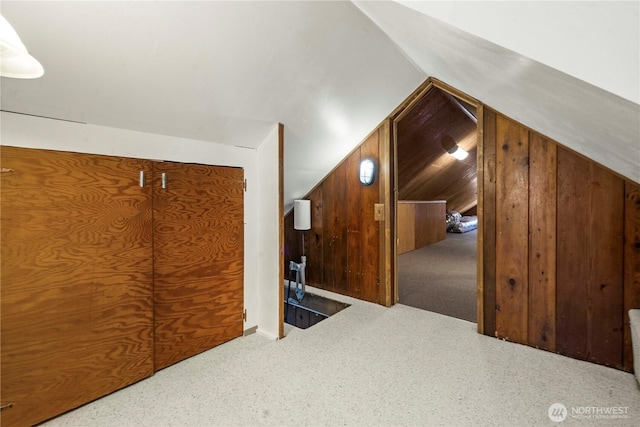 additional living space with lofted ceiling, carpet flooring, and wooden walls