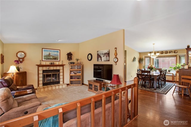 living area with a chandelier, wood finished floors, and a tile fireplace