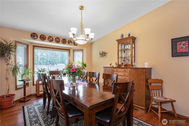 dining room with lofted ceiling, a notable chandelier, baseboards, and wood finished floors