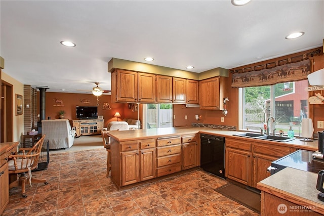 kitchen featuring brown cabinetry, dishwasher, a wood stove, a peninsula, and a sink