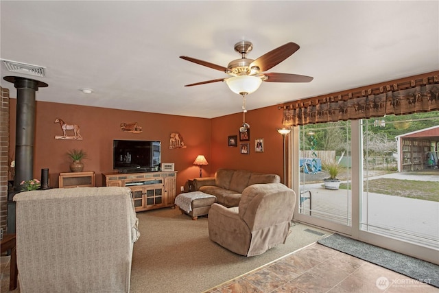 living area featuring visible vents, a wood stove, and a ceiling fan