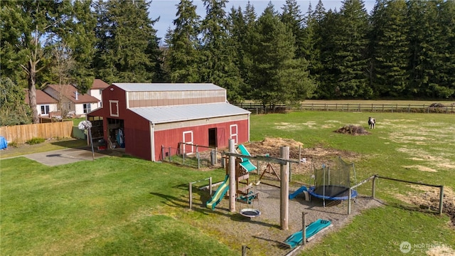 view of playground with a yard, a trampoline, an outdoor structure, and fence