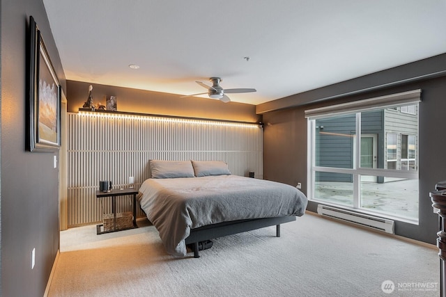 carpeted bedroom with a baseboard heating unit and a ceiling fan