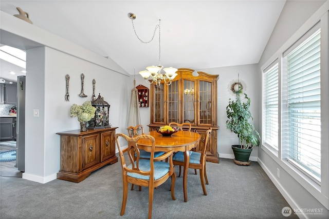 carpeted dining space with vaulted ceiling, plenty of natural light, and a notable chandelier