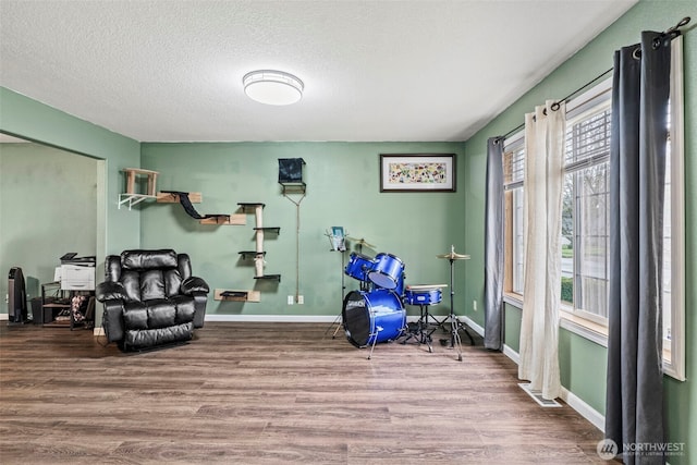 interior space featuring a textured ceiling, baseboards, and wood finished floors