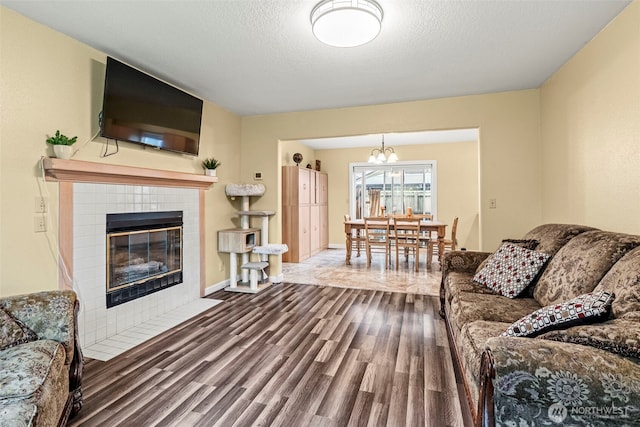 living area with dark wood-style floors, baseboards, a textured ceiling, and a tile fireplace