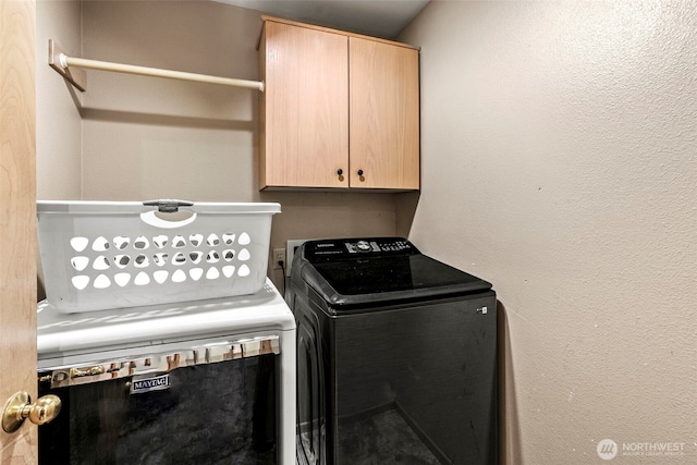 laundry room featuring cabinet space, a textured wall, and independent washer and dryer