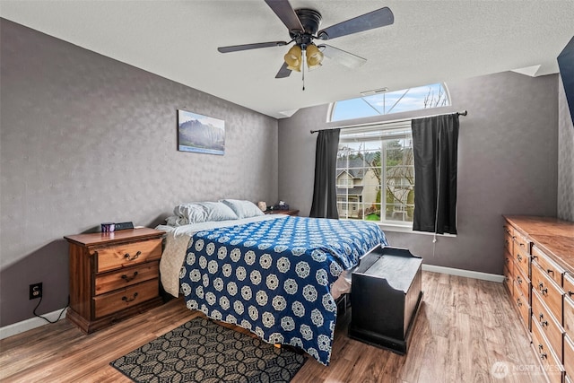 bedroom featuring a textured ceiling, wood finished floors, a ceiling fan, and baseboards