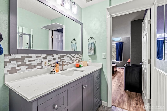 bathroom with vanity, visible vents, backsplash, and wood finished floors