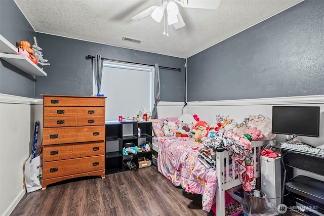 bedroom with a textured ceiling, wood finished floors, visible vents, and a ceiling fan