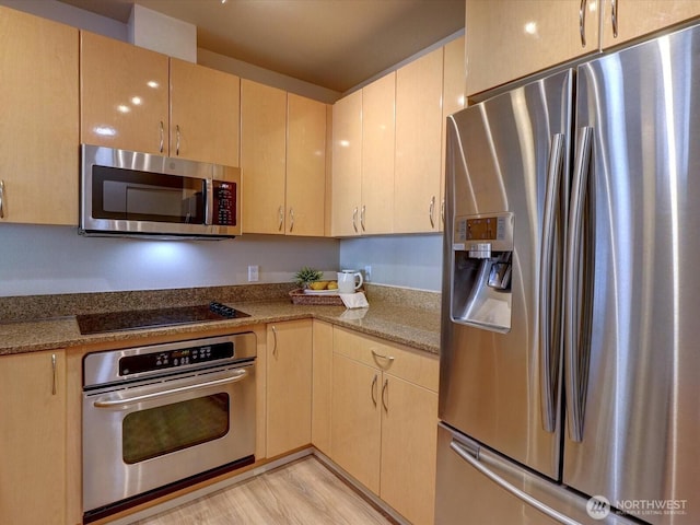 kitchen featuring stainless steel appliances, light brown cabinets, light wood-style floors, and light stone countertops