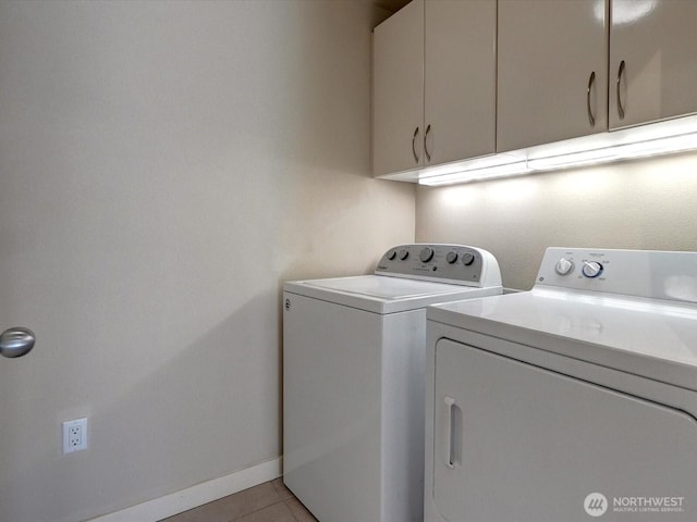 clothes washing area with washer and clothes dryer, light tile patterned flooring, cabinet space, and baseboards