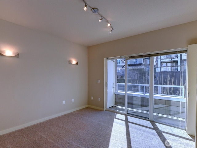 carpeted empty room with track lighting and baseboards