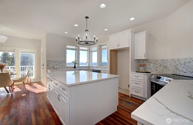 kitchen with light stone counters, a center island, stainless steel range with electric stovetop, and a notable chandelier