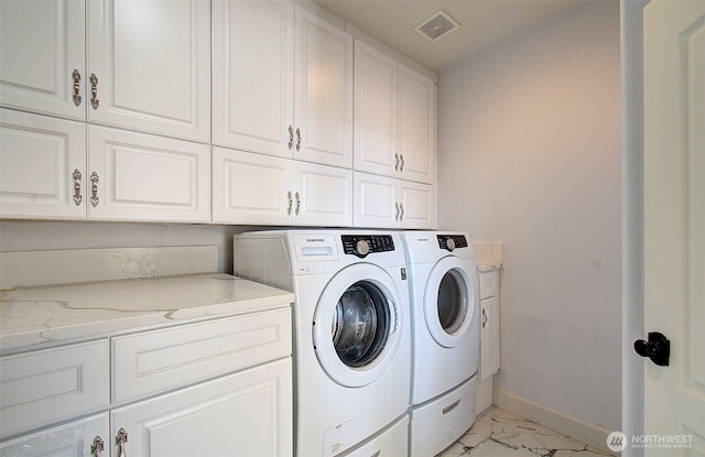 clothes washing area featuring cabinet space, baseboards, visible vents, independent washer and dryer, and marble finish floor