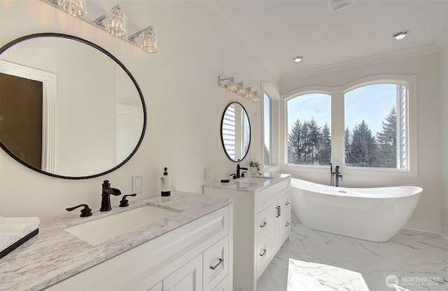 full bath with marble finish floor, crown molding, a freestanding tub, and a sink