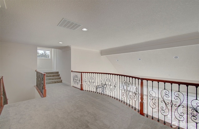 hallway with visible vents, crown molding, a textured ceiling, carpet flooring, and recessed lighting