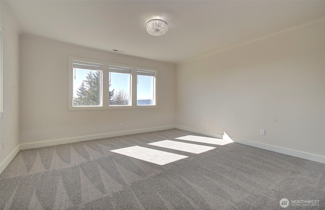 carpeted spare room with ornamental molding, visible vents, and baseboards