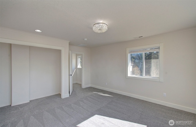 unfurnished bedroom featuring baseboards, carpet flooring, visible vents, and crown molding