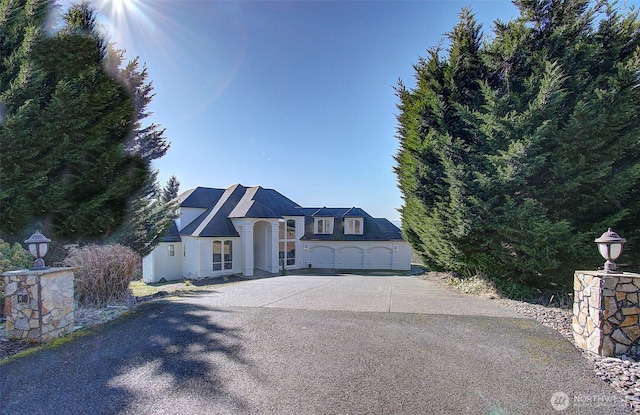 french country inspired facade featuring driveway and an attached garage