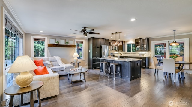 living area with recessed lighting, baseboards, dark wood finished floors, crown molding, and ceiling fan with notable chandelier