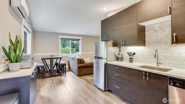 kitchen with dark brown cabinetry, decorative backsplash, a wall mounted air conditioner, stainless steel appliances, and a sink