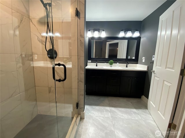 full bath with a stall shower, a sink, and double vanity