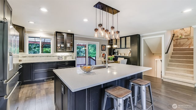 kitchen featuring dark wood-style flooring, a sink, light countertops, stainless steel refrigerator with ice dispenser, and backsplash