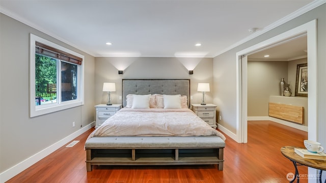 bedroom with crown molding, wood finished floors, visible vents, and baseboards