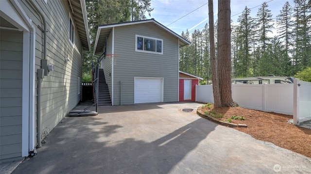 view of home's exterior with driveway, stairway, and fence