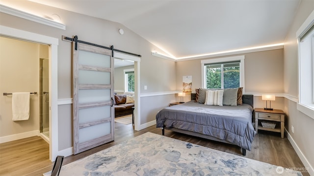 bedroom with a barn door, baseboards, vaulted ceiling, and wood finished floors