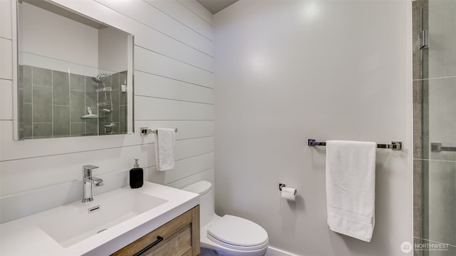 full bath featuring wood walls, a tile shower, vanity, and toilet