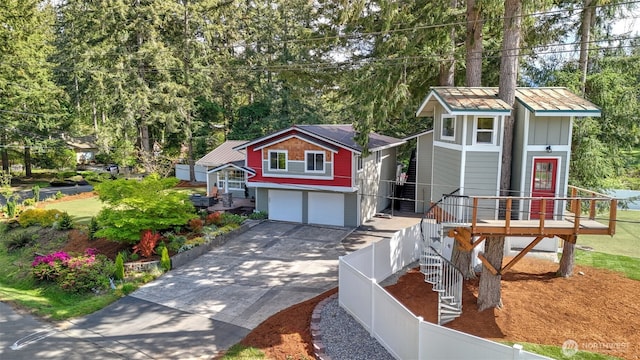 view of front facade featuring a garage, driveway, board and batten siding, and fence