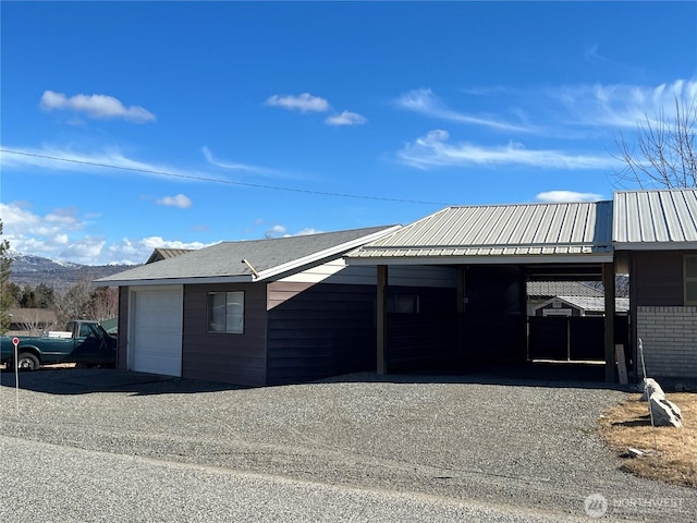 exterior space with a mountain view, a carport, and gravel driveway