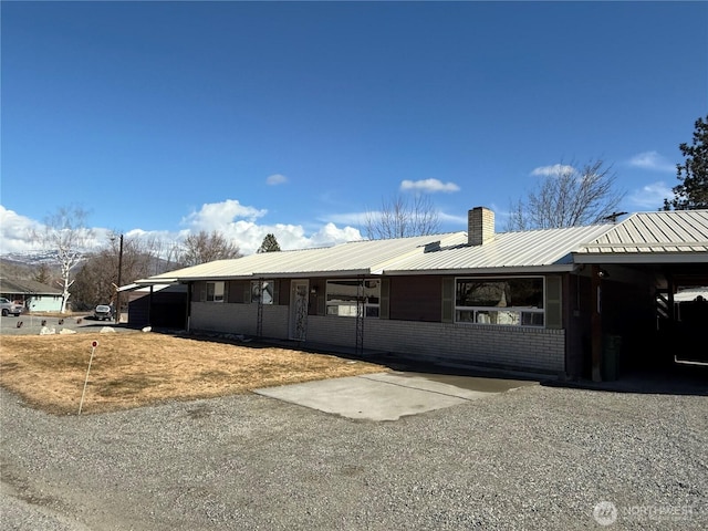 view of front of property featuring metal roof, brick siding, and a chimney