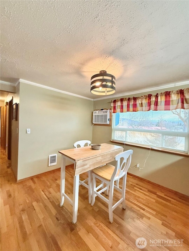 dining space with visible vents, crown molding, a wall mounted air conditioner, light wood-style flooring, and a textured ceiling