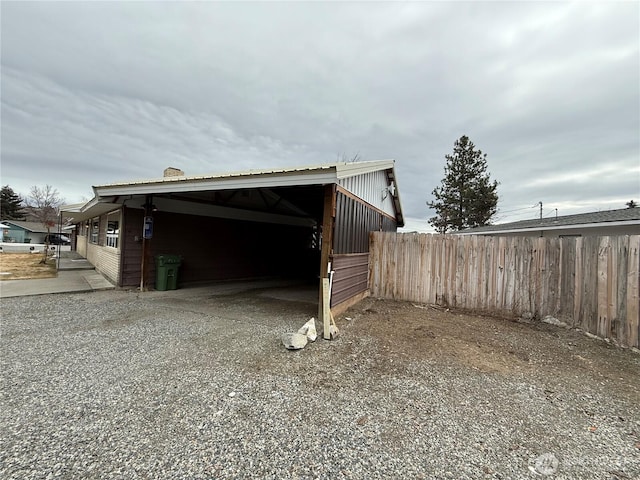 exterior space featuring driveway, an attached carport, a chimney, and fence