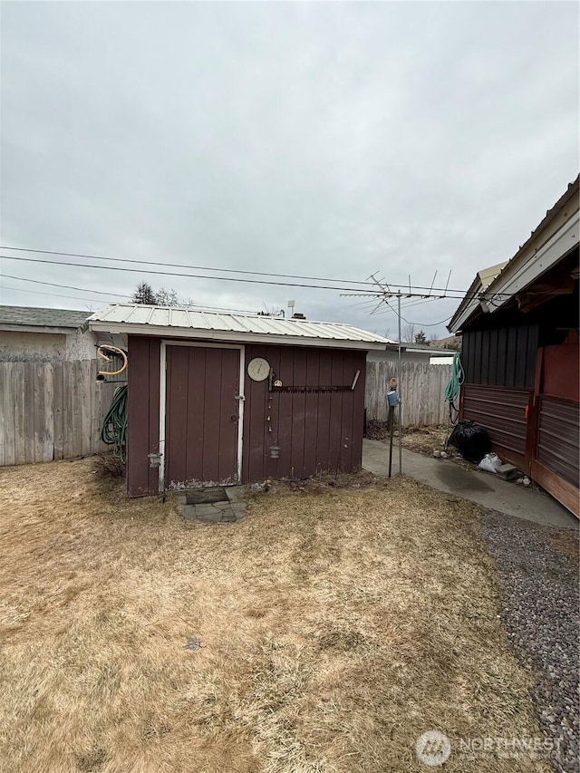 view of yard featuring a storage shed, an outdoor structure, and fence