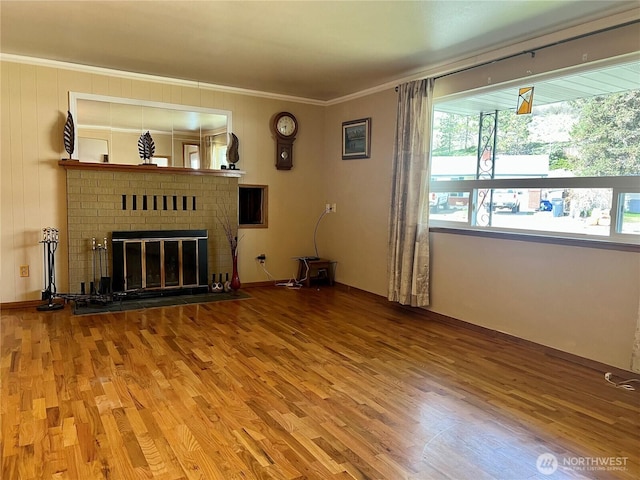 unfurnished living room featuring ornamental molding, wood finished floors, and a fireplace