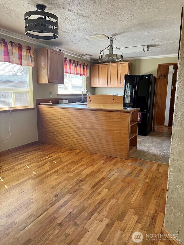 kitchen with a peninsula, freestanding refrigerator, a textured ceiling, and light wood finished floors
