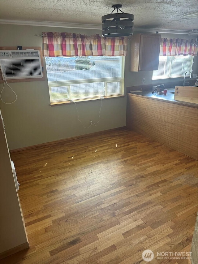 unfurnished dining area with wood finished floors, a wall mounted AC, and a textured ceiling