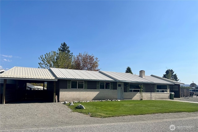 single story home with a chimney, a front lawn, a carport, metal roof, and brick siding